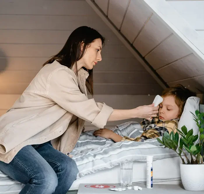 Woman tending to a child's fever with a thermometer