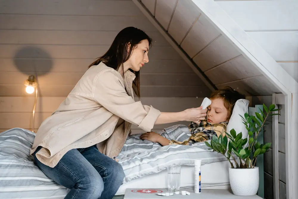 Woman tending to a child's fever with a thermometer